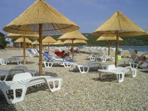 Blick auf den Kiesstrand mit Liegen und Sonnenschirmen auf der Insel Krk Punat