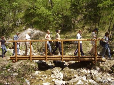 Auf dem Bild ist eine Holzbrücke über einen Bach mit Wanderern bei einem Urlaub in Kroatien